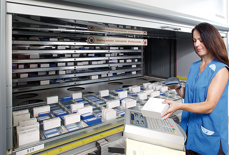 Worker operating a Hänel Lean-Lift vertical lift module system to retrieve stored trays - TYT Corporation